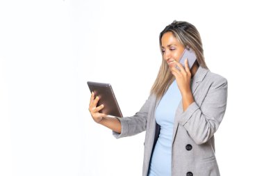 Mujer joven y atractiva emsaria mirando el mvil y consultando la tablet, expresiones de alegra y enfado