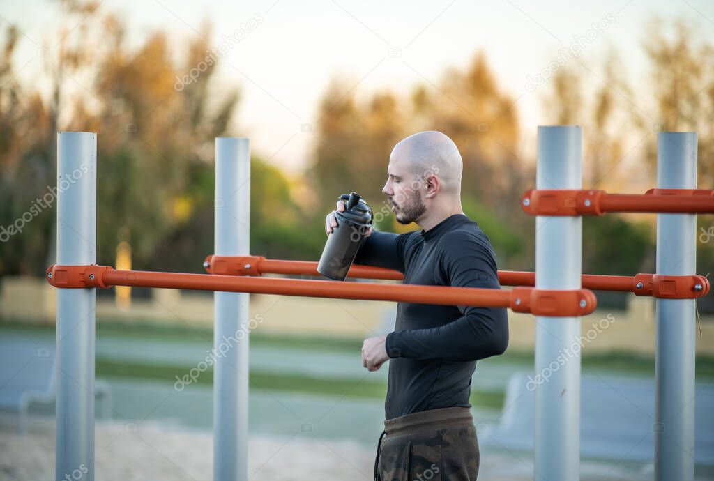 hombre joven y atractivo haciendo deporte en las barras en un parque al aire libre
