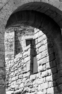 Window under a stone arch in black and white in a medieval village