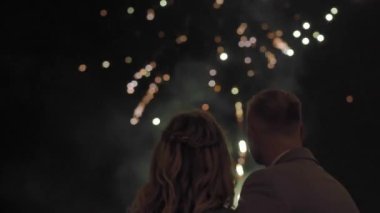 Genç çift gökyüzünde havai fişekleri seyrediyor.