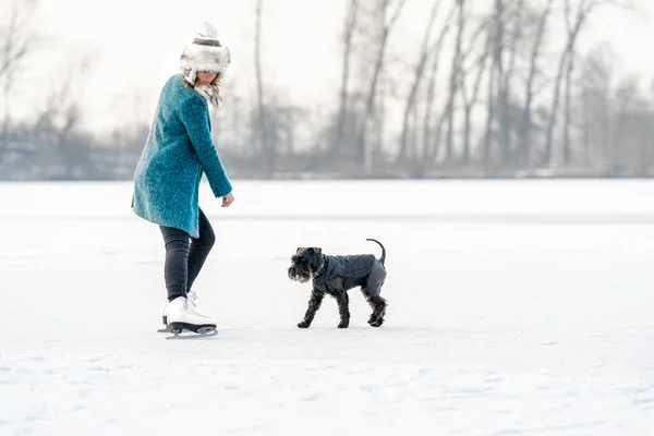 Jonge vrouw en hond op een bevroren meer in de winter — Stockfoto