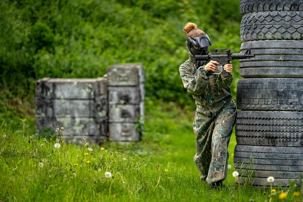 Junge Frau in Aktion beim Paintball spielen — Stockfoto