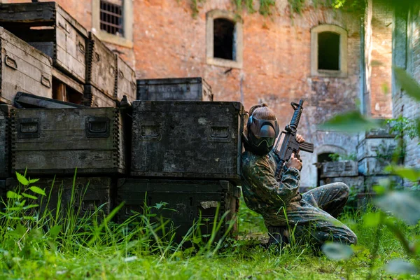 Junge Frau in Aktion beim Paintball spielen — Stockfoto