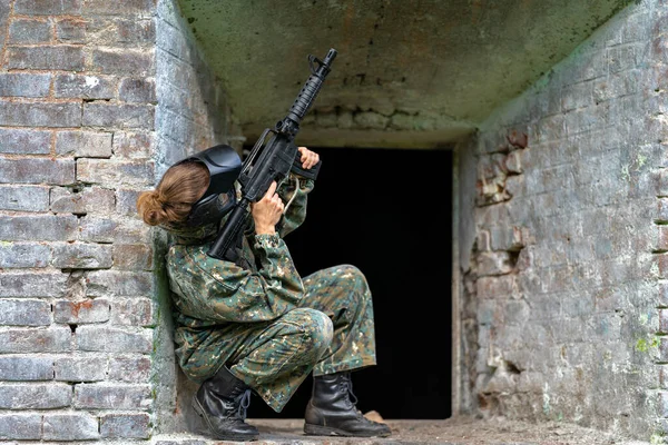 Mujer de uniforme con un arma en entrenamiento militar de paintball —  Fotos de Stock