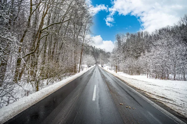 Droga asfaltowa w zimie zaśnieżony las, błękitne niebo — Zdjęcie stockowe