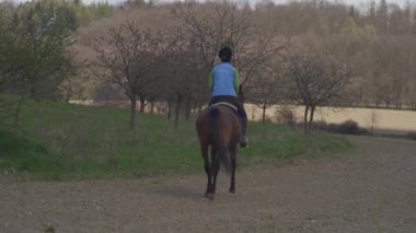 Genç kadın vahşi doğada ata biniyor.