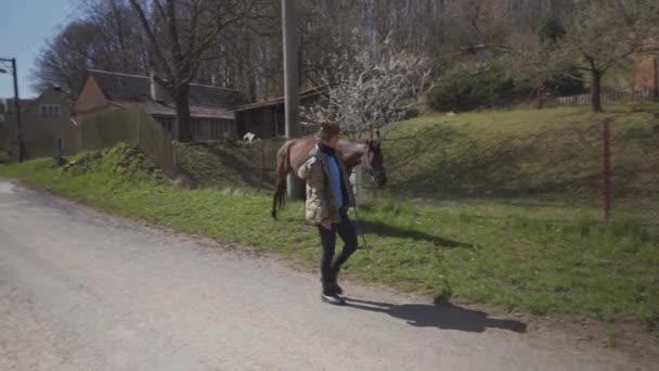 Vrouw leidt een paard door het dorp — Stockvideo