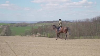 Genç kadın vahşi doğada ata biniyor.