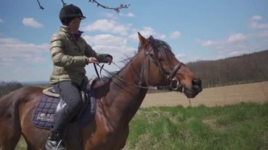 Genç kadın vahşi doğada ata biniyor.
