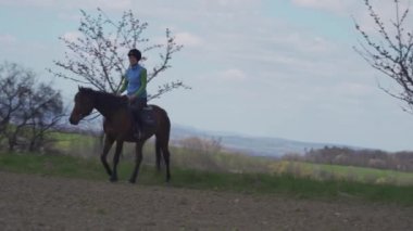 Genç kadın vahşi doğada ata biniyor.