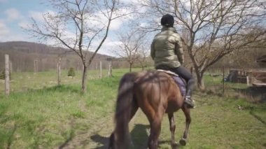 Genç kadın vahşi doğada ata biniyor.