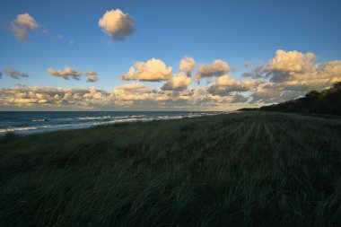 Baltık sahillerinde gün batımı ve gökyüzünde bulutlar. Ek olarak, denizin sesi ve burnun etrafında taze bir esinti..