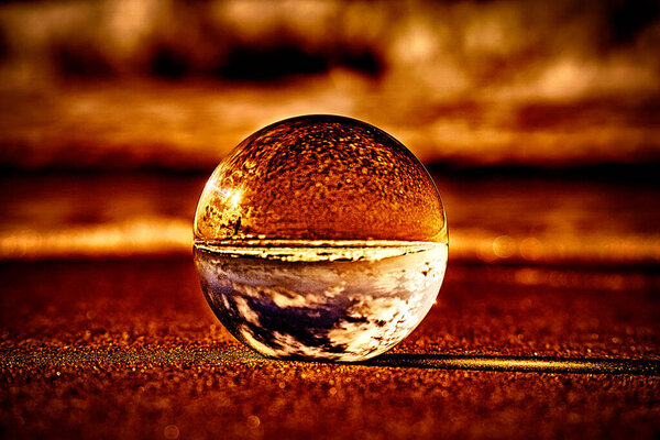 Абстрактное изображение стеклянного шара на пляже у Балтийского моря. Окружающая среда горит. Похоже, что стеклянный шар лежит на горящей лаве