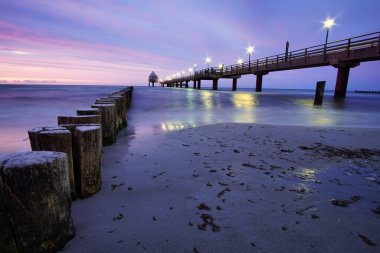 Baltık Denizi 'ndeki Zingst rıhtımında uzun bir pozlama ve mor pastel renklerle. Bu bölgede deniz kenarı eğlencesi