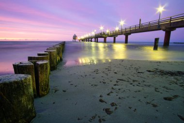 Baltık Denizi 'ndeki Zingst rıhtımında uzun bir pozlama ve mor pastel renklerle. Bu bölgede deniz kenarı eğlencesi