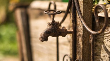 Eski musluk kadar eski, tahta tahtasında pas var. Ayrıntılı ve desenli dekorasyon