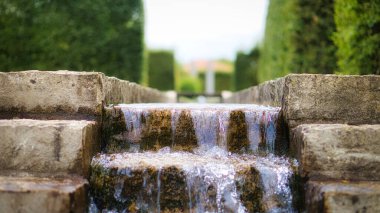 Taş bir merdivenin üzerinde şelale. Parkta akan bir dere. Su damlar ve havada uçar..
