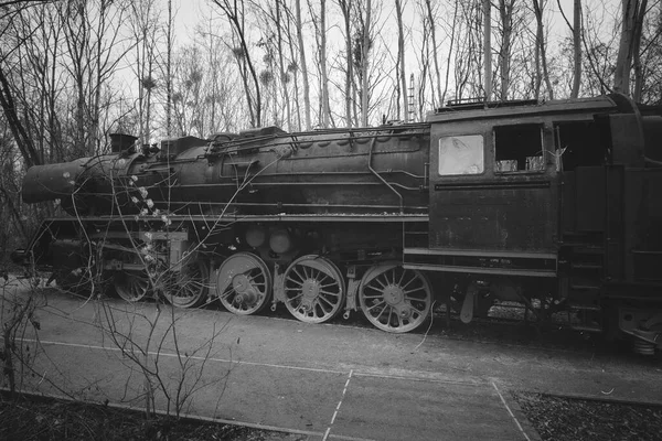 Steam locomotive in black white, parked at a terminal station. Historical railroad from 1940 in black red. Nostalgia photo of past technology