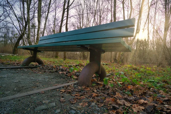 Wooden park bench over abandoned railroad tracks in a park in autumn. Lonely enjoy the peace and quiet in nature. Still life photo.