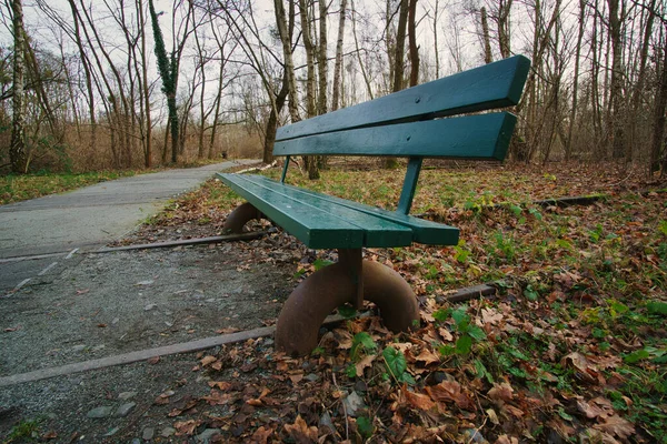 Wooden park bench over abandoned railroad tracks in a park in autumn. Lonely enjoy the peace and quiet in nature. Still life photo.