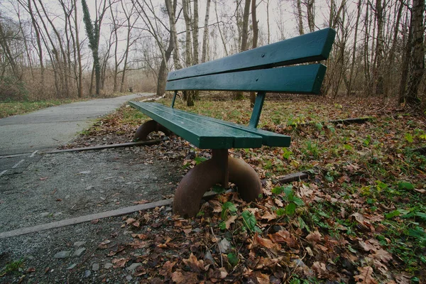 Wooden park bench over abandoned railroad tracks in a park in autumn. Lonely enjoy the peace and quiet in nature. Still life photo.