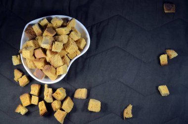 Buğday krakerleri, masada kalp şeklinde tabak, kahverengi arka plan..