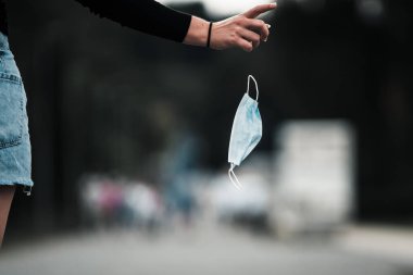 Kız ayakta duruyor ve tıbbi solunum maskelerini atıyor. Günlerdir koronavirüs yok, umut yok, cerrahi koruyucu maske. Koronavirüs salgınının yayılmasını önlemek için COVID-19 