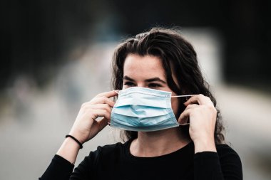 Kadın koruyucu maske takıyor, koronavirüsü önlüyor, tıbbi maske, covid-19.