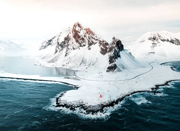 İzlanda 'nın doğusundaki Eystrahorn Dağı kışın kumsalda ve denizde karla kaplı, insansız hava aracının çektiği bir fotoğraf.