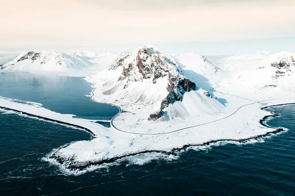 İzlanda 'nın doğusundaki Eystrahorn Dağı kışın kumsalda ve denizde karla kaplı, insansız hava aracının çektiği bir fotoğraf.