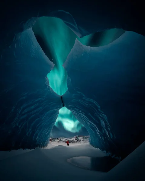 Osoba Środku Jaskini Lodowej Zorzą Polarną Podczas Oszałamiającego Zimowego Wieczoru — Zdjęcie stockowe