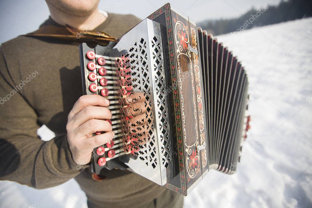 Man is playing on beautiful old harmonica/accordion in winter nature