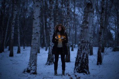 Sihirli zaman, kız donmuş ormanın ortasında duruyor karla ve elinde bir fincan çayla, Noel zamanı