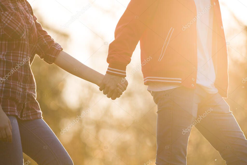 I love you! Love is in the air. Boy is holding girls hand in beautiful warm sunset light. Love between people. Relationship goals, two young people in love. Live and walking together. Summer is coming