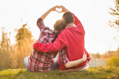 Erkek ve kız, kadın ve erkek arasında güzel bir ilişki. Havada aşk kokusu var. Birbirlerine âşıklar. Ben de seni seviyorum. İnanılmaz yaz günbatımında kalbi elleriyle gösteren iki kişi.. 