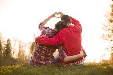 Erkek ve kız, kadın ve erkek arasında güzel bir ilişki. Havada aşk kokusu var. Birbirlerine âşıklar. Ben de seni seviyorum. İnanılmaz yaz günbatımında kalbi elleriyle gösteren iki kişi.. 
