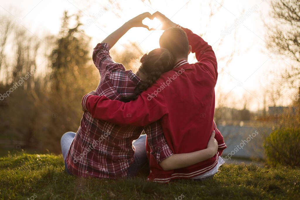 Beautiful relationship between boy and girl, women and men. Love is in the air. They are in love. I love you. Two persons showing heart by hands in amazing summer sunset warm light. 