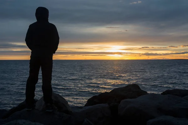 Hayatın tadını çıkar! Kız, Reykjavik, İzlanda yakınlarında okyanusun arkasında inanılmaz bir günbatımının keyfini çıkarıyor.