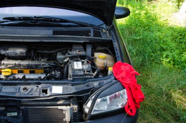 Siyah bir arabanın kaputunu aç ve arabanın üzerinde kırmızı bir paçavra var.