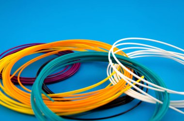 Üç boyutlu bir yazıcıya yakın plan baskı yapmak için çok renkli plastik iplikler. Karmaşık renkli termoplastik iplikli 3D yazıcı makaraları. Mavi olan.