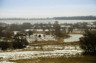 Soğuk kış günü karla kaplı topraklar ve ağaçlar, kış köyü