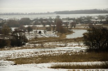Soğuk kış günü karla kaplı topraklar ve ağaçlar, kış köyü