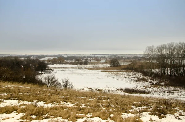 Soğuk kış günü karla kaplı topraklar ve ağaçlar, kış köyü