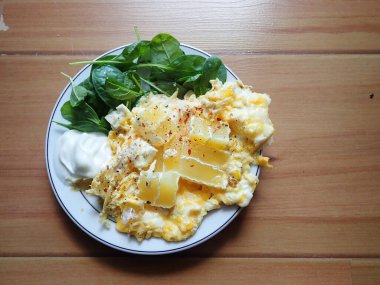 postion of scrambles eggs with salad on a plate