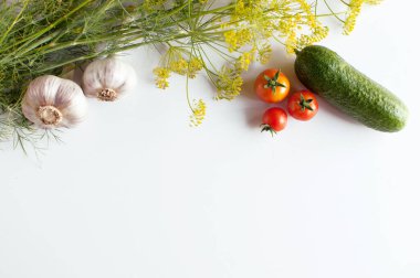 Yeşil dereotlu sarı şemsiyeler, iki baş sarımsak, üç kırmızı domates ve beyaz bir arka planda yeşil salatalık.