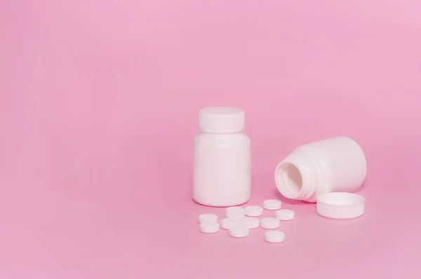 Dwie Nieoznakowane Białe Butelki Leku Rozrzucone Tabletki Różowym Tle — Zdjęcie stockowe