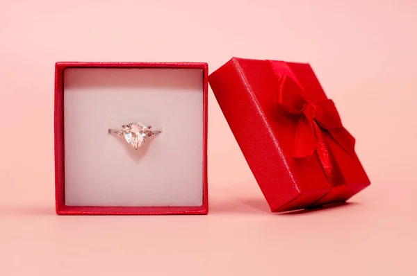 ピンクの背景に赤い箱の中に宝石が入ったホワイトゴールドのリング — ストック写真