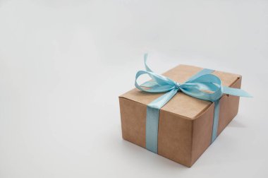 Beyaz arka planda mavi kurdeleyle bağlanmış kahverengi el işi kutu.