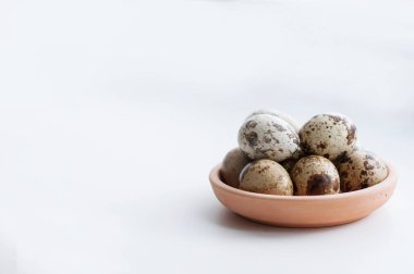 Beyaz arka planda kil tabakta bıldırcın yumurtası.