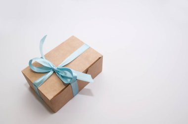 Beyaz arka planda mavi bir fiyonk ve imzası olan bir hediye kutusu.